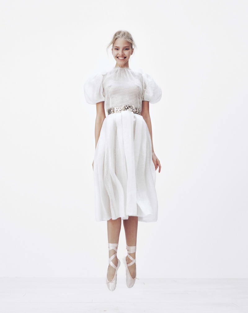Model Sasha Luss poses in white Dolce & Gabbana dress with puffed sleeves