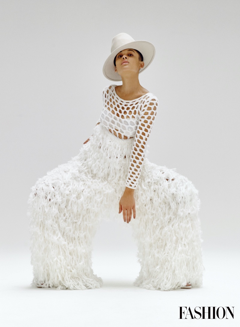 Dressed in white, Jordan Alexander poses in JW Anderson jumpsuit with Alexandre Birman shoes and Esenshel hat.