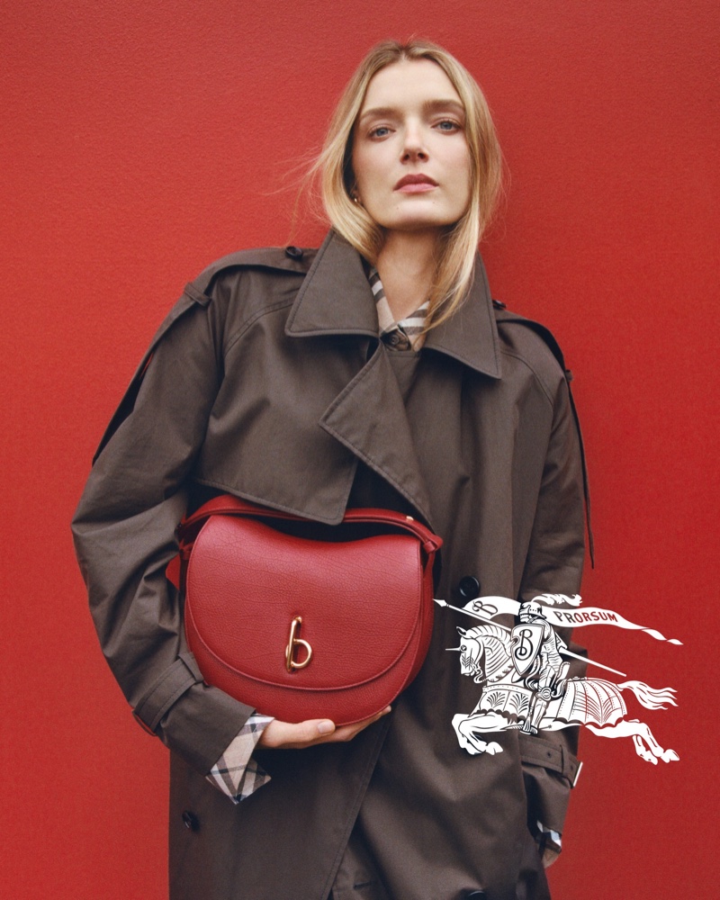 Model Lily Donaldson poses in a trench coat with a red Burberry Rocking Horse bag.