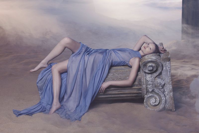 Sara Grace Wallerstedt reclines elegantly in a draped blue gown for Énnush's new Althea collection.