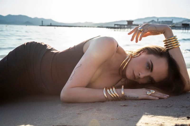 Cara Delevingne lays in the sand while modeling APM Monaco's ÉTÉ collection of jewelry.