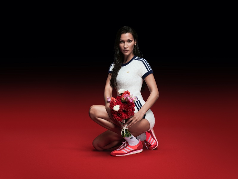 Posing with flowers, Bella Hadid models red adidas Originals SL 72 sneakers.