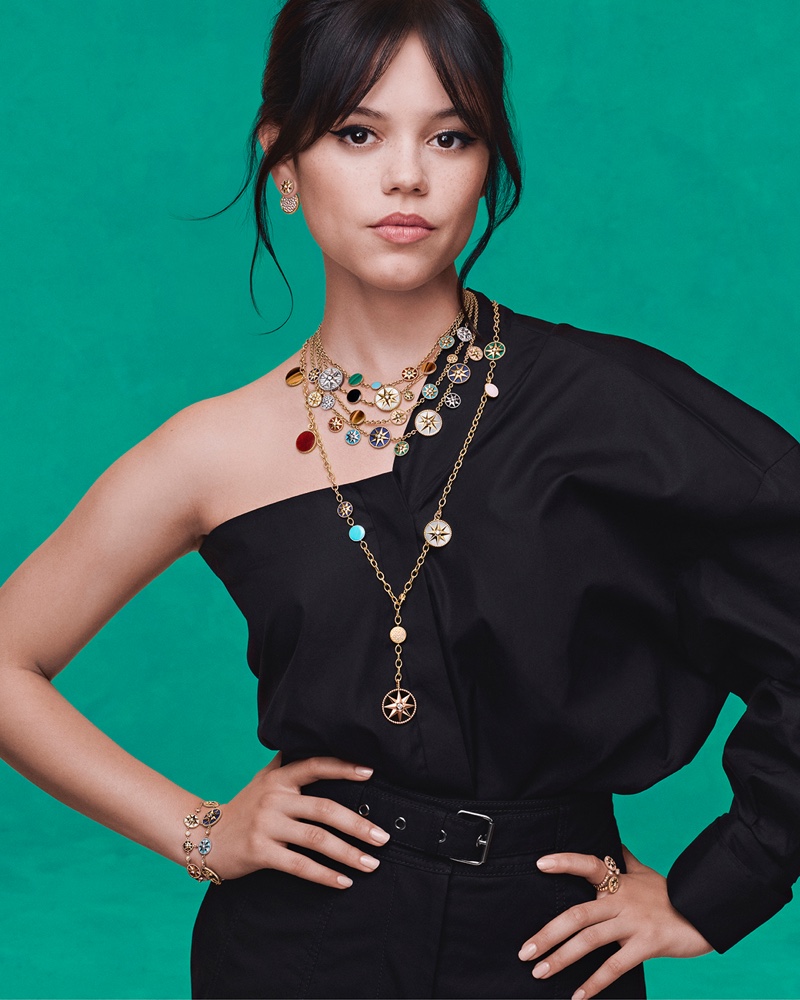 Layered in multicolored pendants, Jenna Ortega models Dior's Rose des Vents designs.