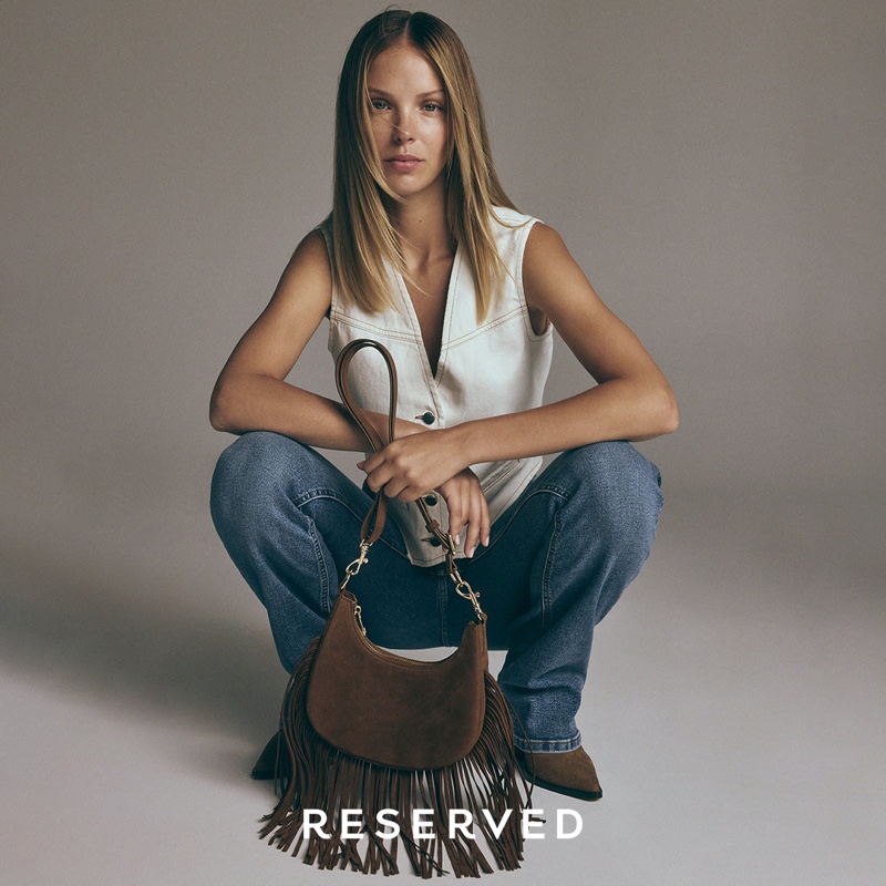 A fringed bag paired with a white vest and denim channels western vibes from Reserved.