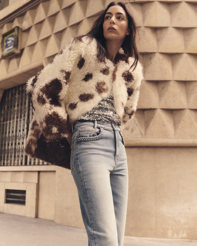 Nora Attal wears a faux fur jacket, sequined top, and blue jeans for Maje's fall 2024 campaign.