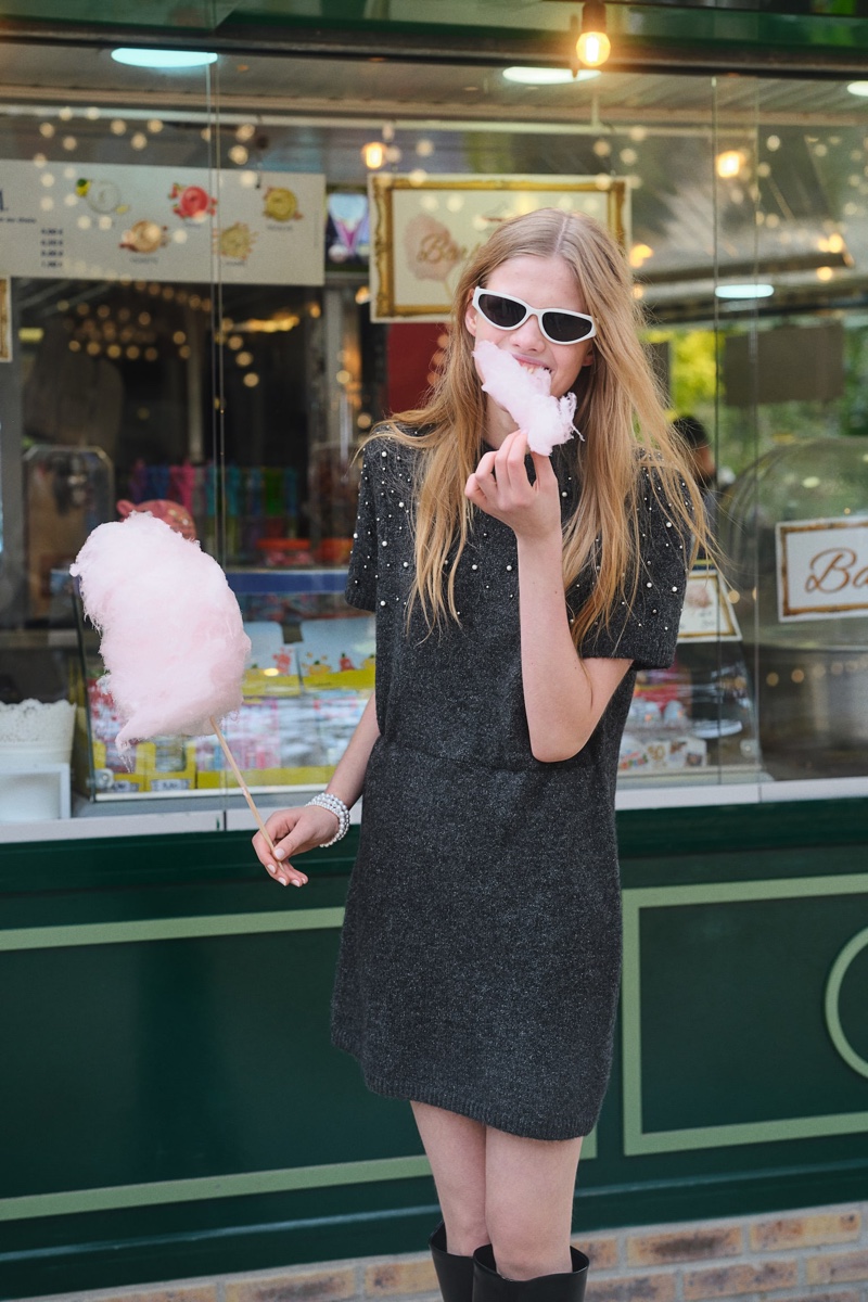 Eating cotton candy, Sofi Damzina wears an H&M beaded fine-knit dress.